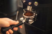  Un moulin à café en train de remplir un porte-filtre avec du café moulu